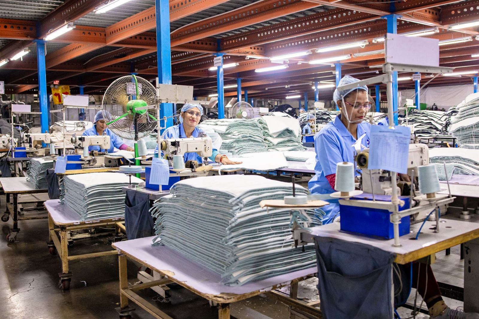 Workers in a textile factory operating sewing machines and organizing fabric.