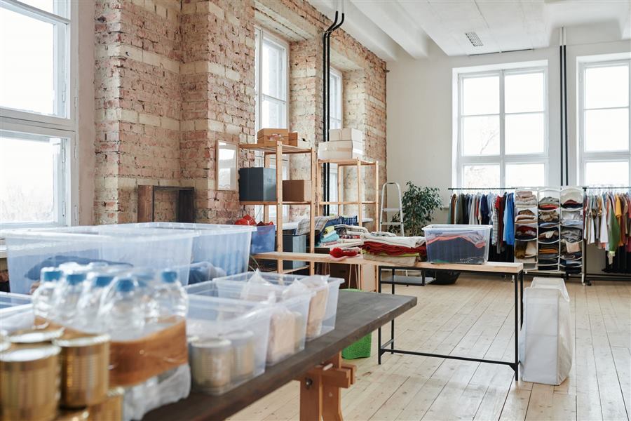 Spacious warehouse interior with wooden floors, racks of clothes, and storage boxes near l
