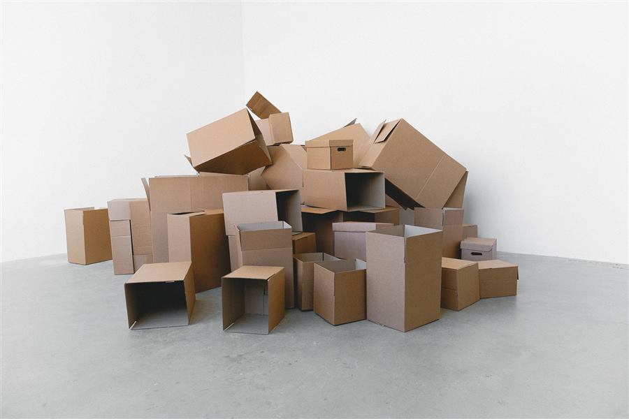 Pile of cardboard containers prepared for relocation on floor at home in daylight on white